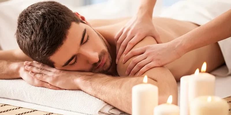 Client relaxing during peaceful shoulder massage with candles